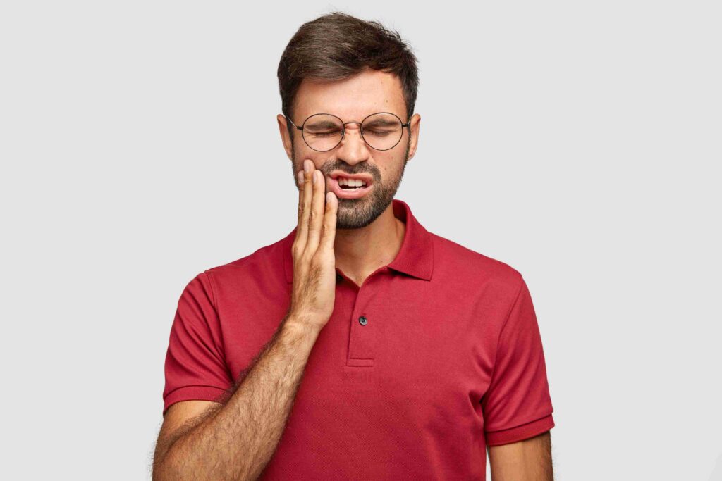 Man holding his cheek due to severe tooth pain.