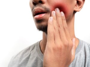 Man holding cheek with tooth pain and swelling